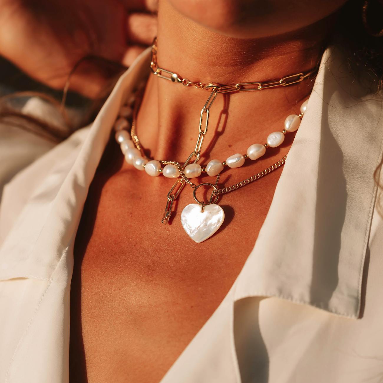 a close up womans neck wearing jewelry in sunset